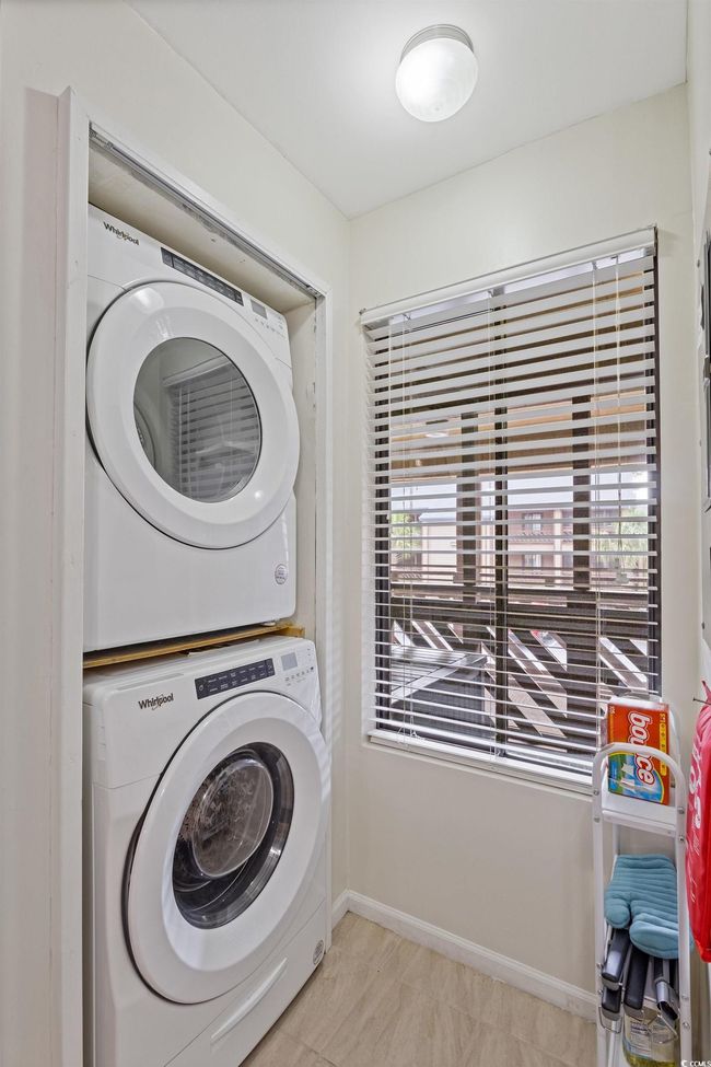 Laundry room with stacked washer and dryer, laundry area, light tile patterned floors, and baseboards | Image 9