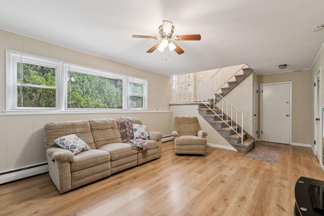 Living area featuring wood finished floors, a ceiling fan, stairs, plenty of natural light, and ornamental molding | Image 21