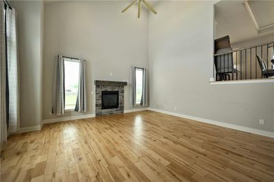 Unfurnished living room with light hardwood / wood-style flooring, ceiling fan, and a fireplace | Image 2