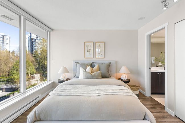 Bedroom featuring baseboard heating, wood finished floors, a city view, ensuite bath, and visible vents | Image 10