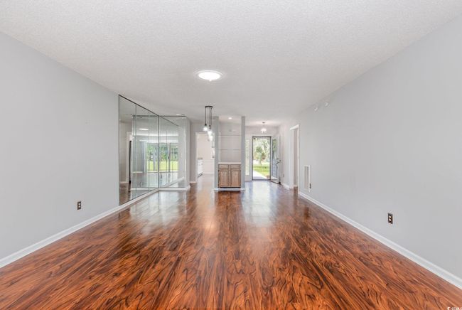 Unfurnished living room with baseboards, a textured ceiling, and dark wood-style flooring | Image 8