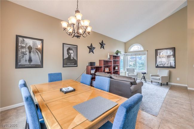 Dining room featuring vaulted ceiling, light tile patterned flooring, baseboards, and a chandelier | Image 12