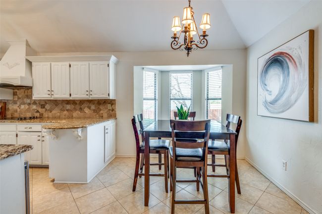 Dining area with lofted ceiling, light tile patterned floors, baseboards, and an inviting chandelier | Image 14