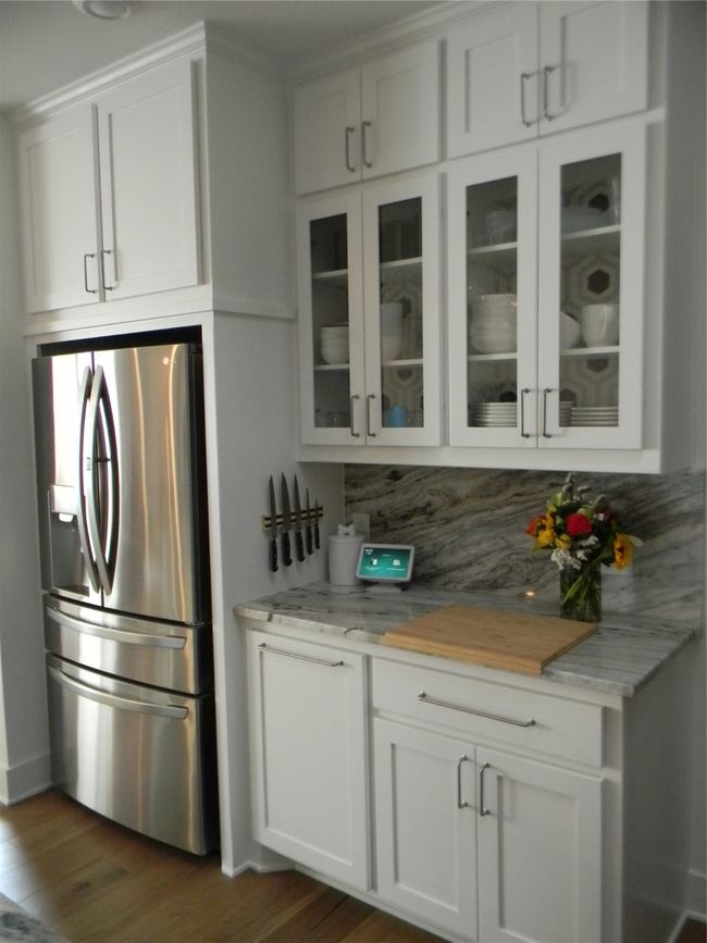 Glass front upper cabinets with stone countertops and backsplash featuring white cabinetry | Image 9