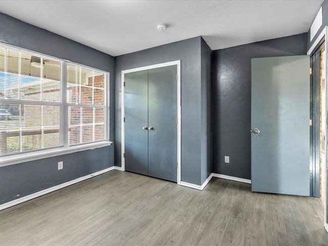 Unfurnished bedroom with a closet, wood finished floors, and baseboards | Image 12