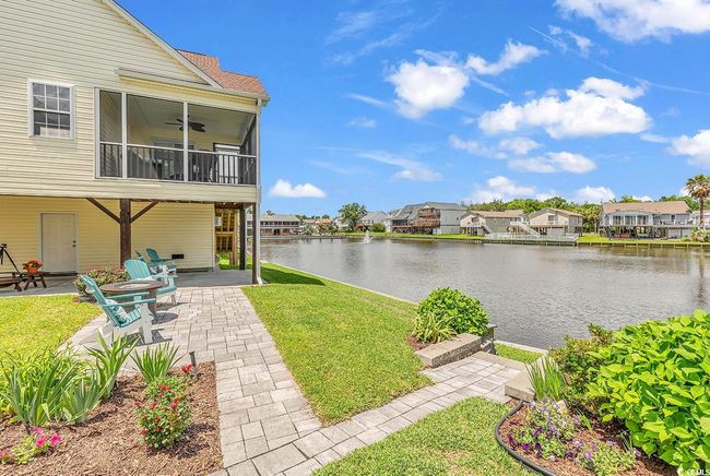 View of green lawn featuring a patio area, a water view, a residential view, and a ceiling fan | Image 31