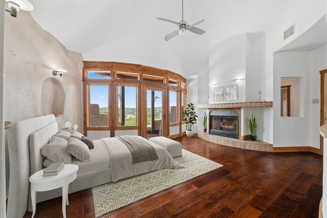 Primary Bedroom featuring dark wood finished floors, high vaulted ceiling, a tiled fireplace, and access to outside | Image 10