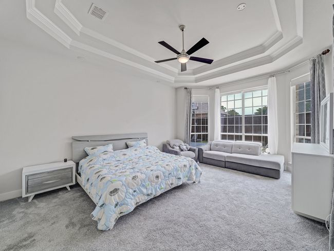 Carpeted bedroom with a tray ceiling, ornamental molding, and ceiling fan | Image 10