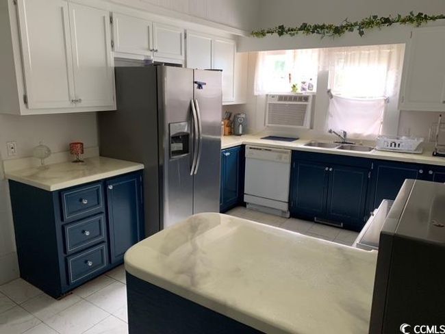 Kitchen featuring blue cabinetry, white dishwasher, a sink, stainless steel fridge, and white cabinetry | Image 5