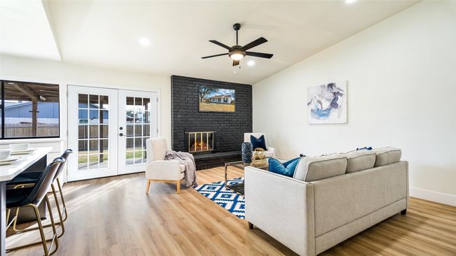 Living room with lofted ceiling, a fireplace, french doors, ceiling fan, and wood finished floors | Image 6