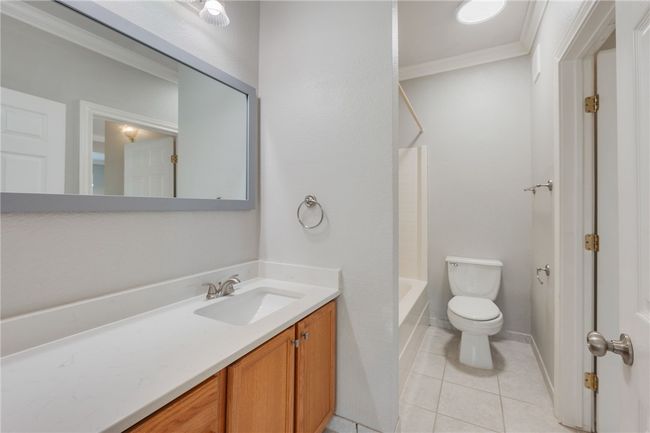 Bathroom with vanity, tile patterned flooring, ornamental molding, and shower combination | Image 10