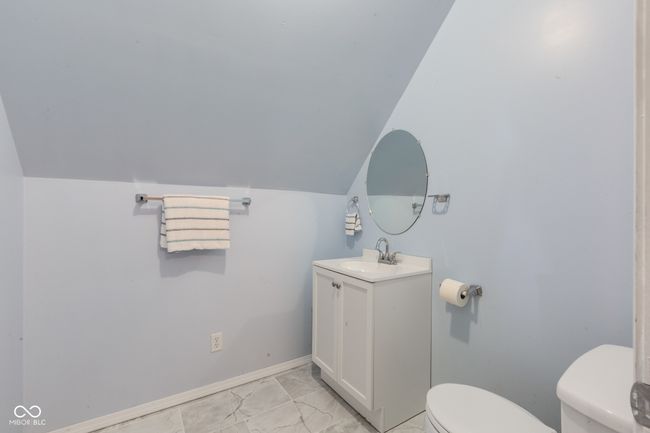 half bath featuring vanity, baseboards, vaulted ceiling, toilet, and marble finish floor | Image 19