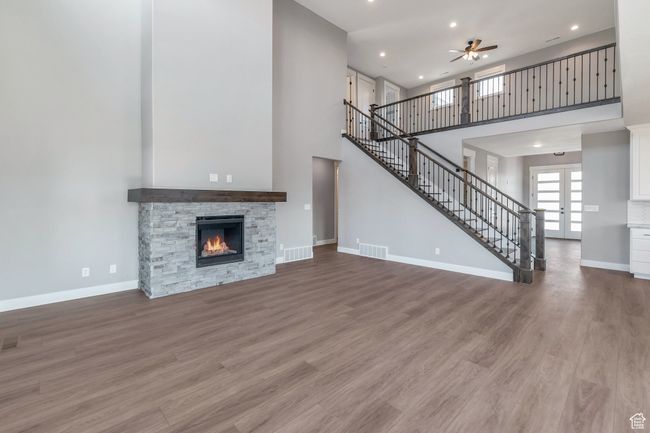Unfurnished living room featuring a high ceiling, a ceiling fan, stairs, recessed lighting, and wood finished floors | Image 14