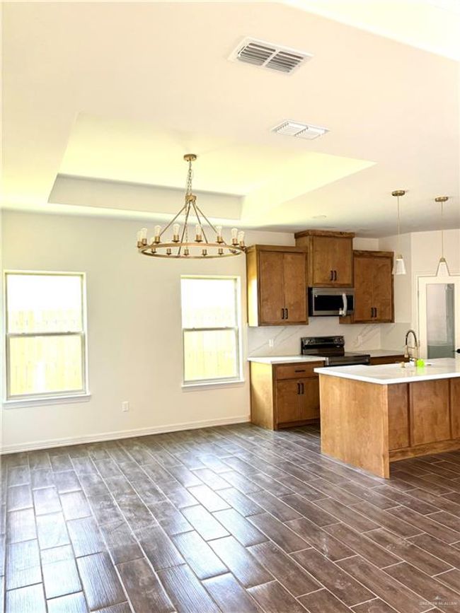 Kitchen with a tray ceiling, brown cabinets, stainless steel microwave, visible vents, and electric range | Image 16