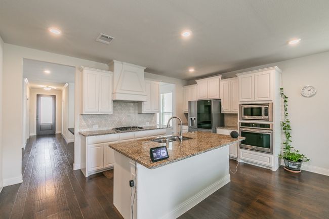 Kitchen with visible vents, a sink, decorative backsplash, stainless steel appliances, and custom range hood | Image 20