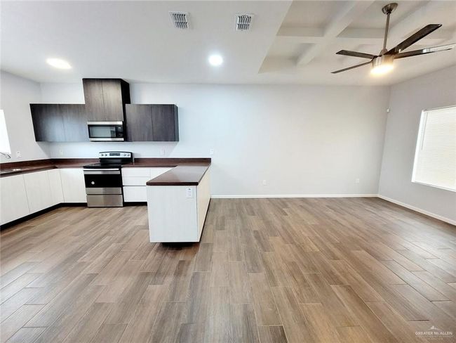 Kitchen with visible vents, open floor plan, dark countertops, appliances with stainless steel finishes, and light wood finished floors | Image 6