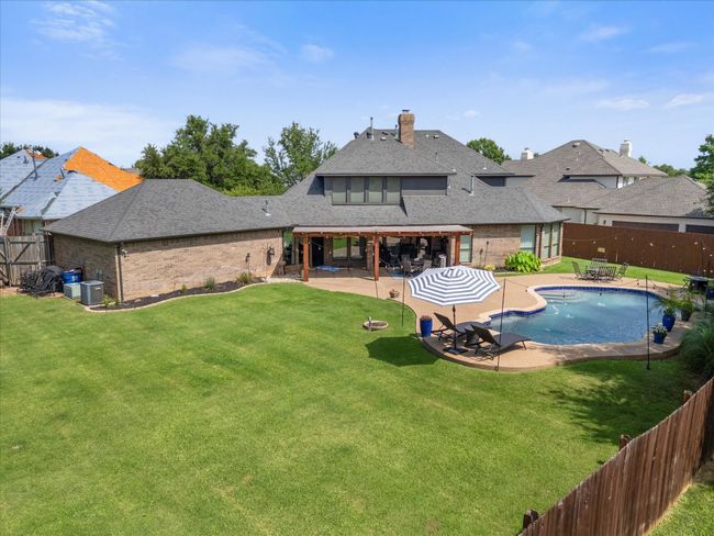 Rear view of house with a fenced backyard, brick siding, a patio area, and a shingled roof | Image 35