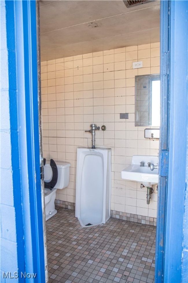 Bathroom with tile patterned flooring, toilet, tile walls, and sink | Image 15