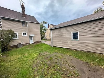 Rear view of house with central air condition unit and a lawn | Image 3