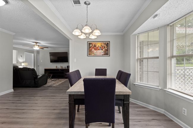 Dining space featuring a textured ceiling, visible vents, wood finished floors, baseboards, and ornamental molding | Image 11
