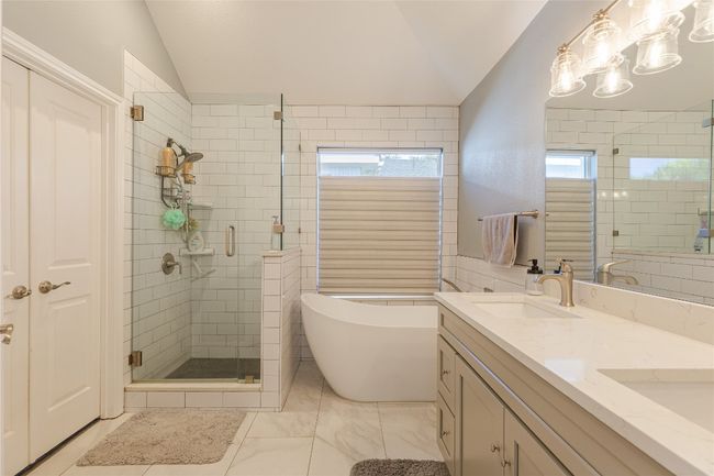 Full bathroom featuring lofted ceiling, a stall shower, a soaking tub, and double vanity | Image 20