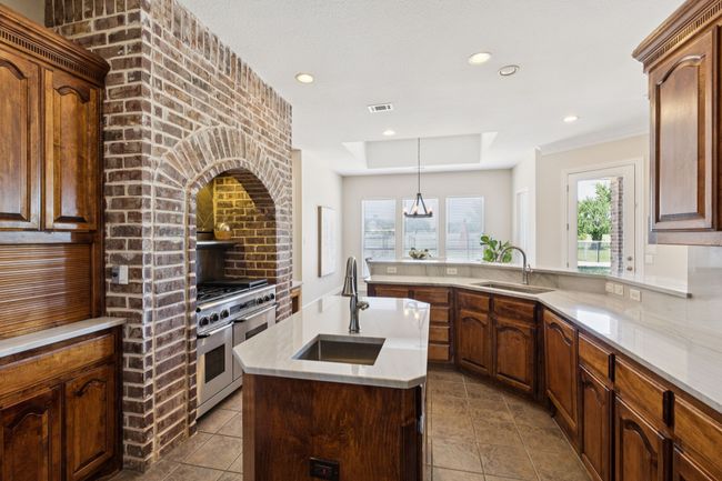 The kitchen boasts rich cabinetry providing wonderful storage and there is so much work space with the island and gorgeous counters. The kitchen also enjoys the amazing views and abundant natural light from the windows lining the back of the home. | Image 13