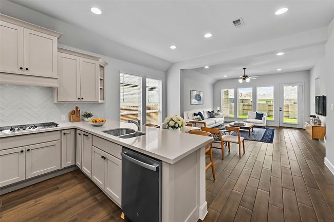 Kitchen featuring a peninsula, dishwashing machine, open floor plan, dark wood-style floors, and light countertops | Image 8