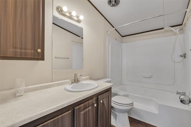 Full bathroom featuring shower / tub combination, vanity, and a textured ceiling | Image 8