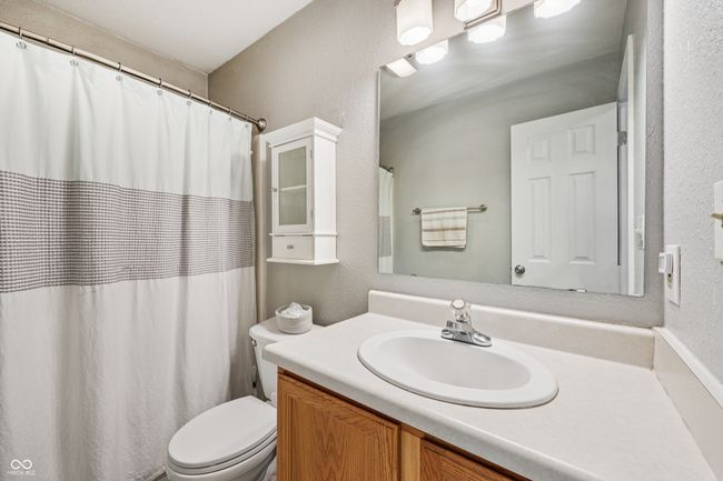 full bathroom with vanity, a textured wall, and a shower with curtain | Image 24