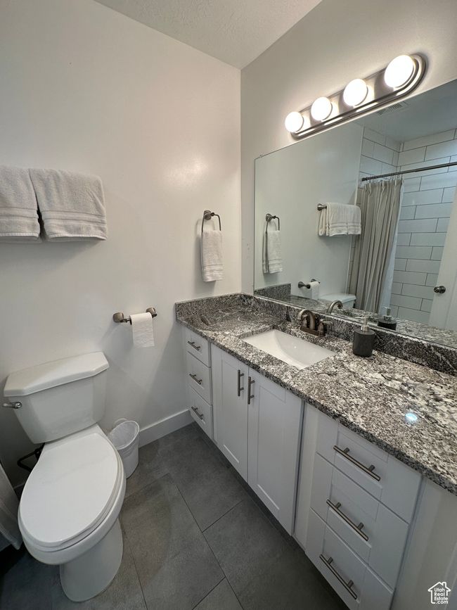 Full bath featuring toilet, vanity, baseboards, tiled shower, and tile patterned flooring | Image 24