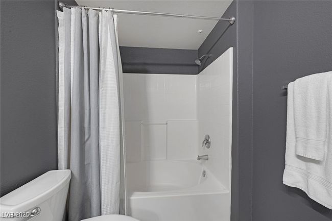 Bathroom featuring toilet and shower / tub combo with curtain | Image 21