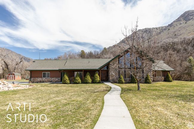View of front of house with a mountain view, a front lawn, an outdoor structure, and stone siding | Image 12