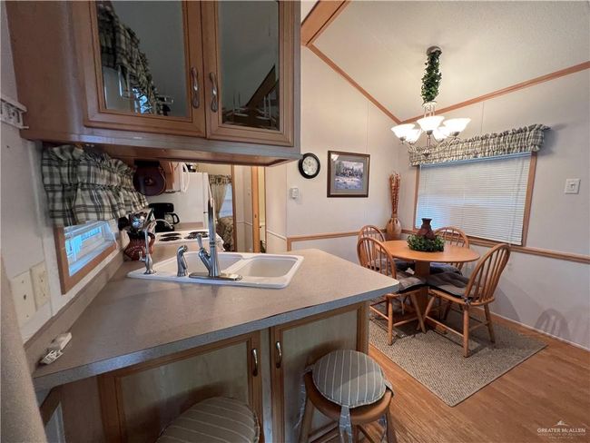 Kitchen featuring a notable chandelier, wood-type flooring, vaulted ceiling, and a kitchen breakfast bar | Image 5