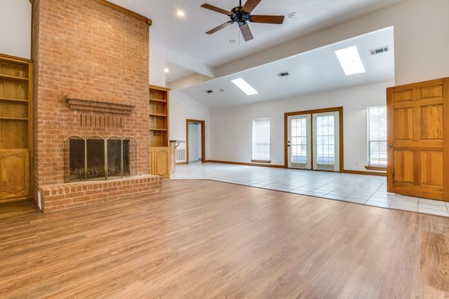 Unfurnished living room with a skylight, built in features, a ceiling fan, light wood finished floors, and a fireplace | Image 4