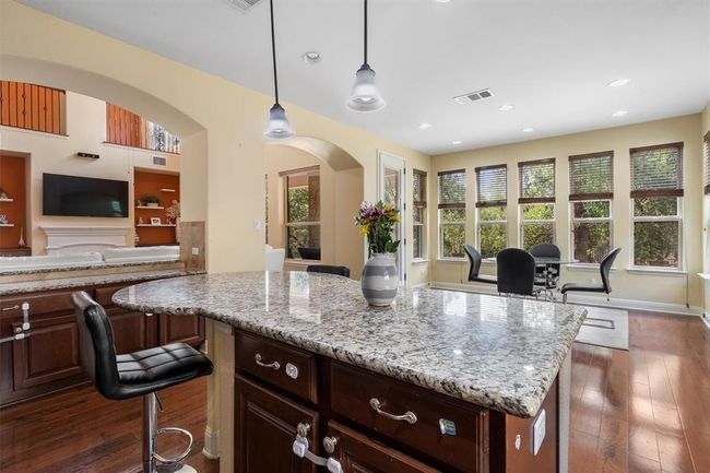 Kitchen featuring arched walkways, dark wood-style flooring, light stone counters, and recessed lighting | Image 14
