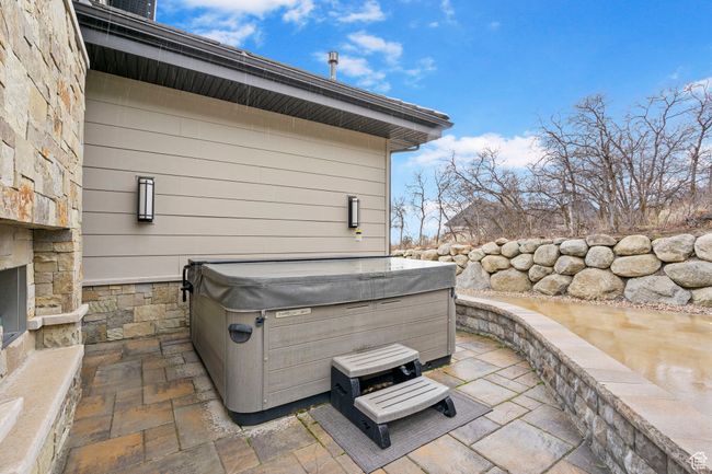 View of patio with an outdoor stone fireplace and a hot tub | Image 92