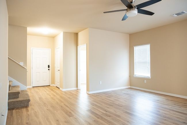 Unfurnished room featuring light wood finished floors, a ceiling fan, stairway, and baseboards | Image 10