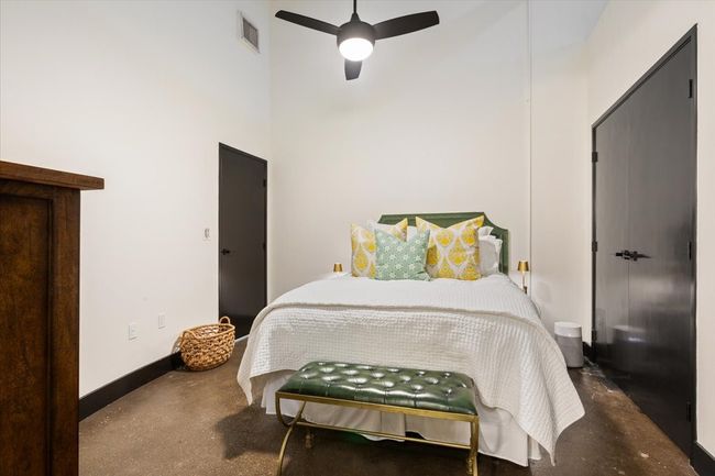 Bedroom featuring concrete flooring, a towering ceiling, and ceiling fan | Image 12
