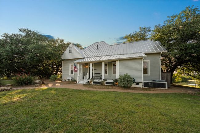 Back of house featuring covered porch, a lawn, and a metal roof | Image 25