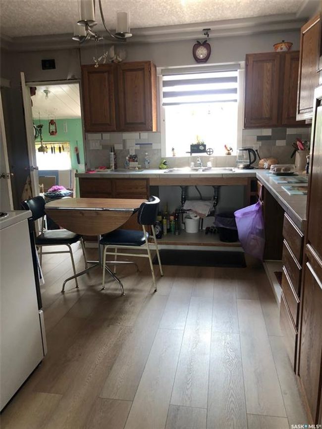 Kitchen featuring stove, a textured ceiling, light wood-style flooring, tasteful backsplash, and brown cabinetry | Image 20
