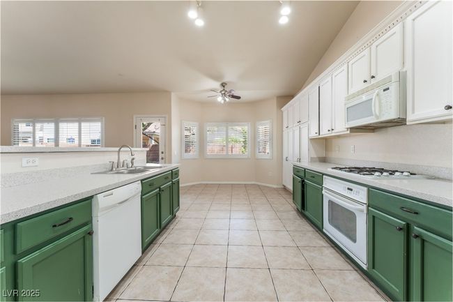 Kitchen featuring white appliances, green cabinets, a sink, white cabinets, and a ceiling fan | Image 16