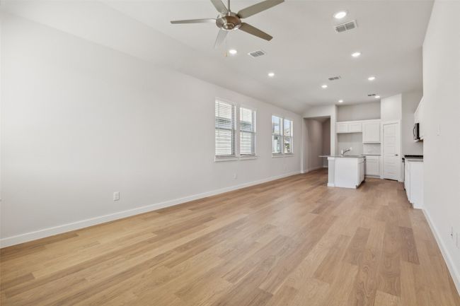 Unfurnished living room featuring a ceiling fan, baseboards, recessed lighting, light wood-style floors, and a sink | Image 8