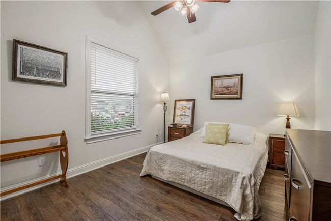 Bedroom featuring ceiling fan, baseboards, wood finished floors, and vaulted ceiling | Image 22