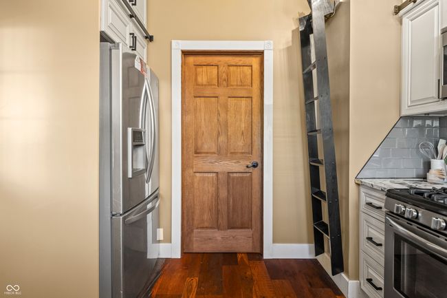 kitchen with dark wood finished floors, stainless steel appliances, light stone counters, a barn door, and decorative backsplash | Image 21