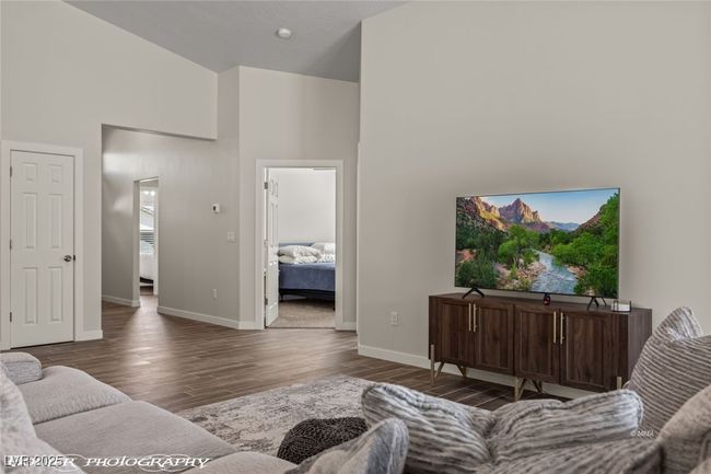 Living area with a high ceiling, wood finished floors, and baseboards | Image 23