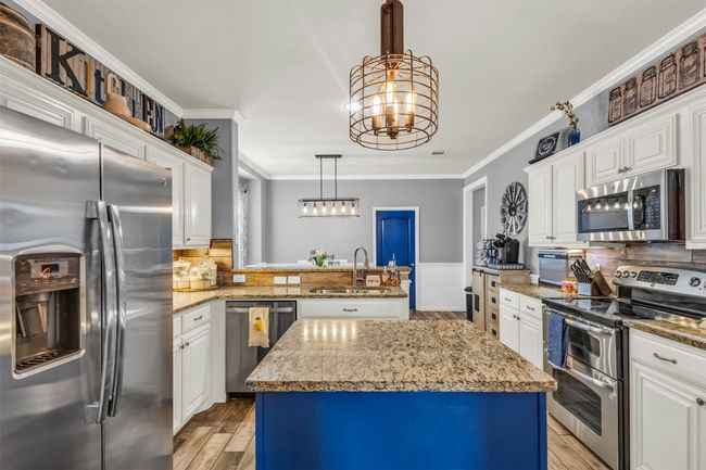 Kitchen featuring a center island, light stone countertops, stainless steel appliances, and crown molding | Image 18