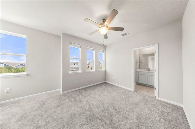 Unfurnished bedroom featuring light colored carpet, ensuite bath, baseboards, and a ceiling fan | Image 16