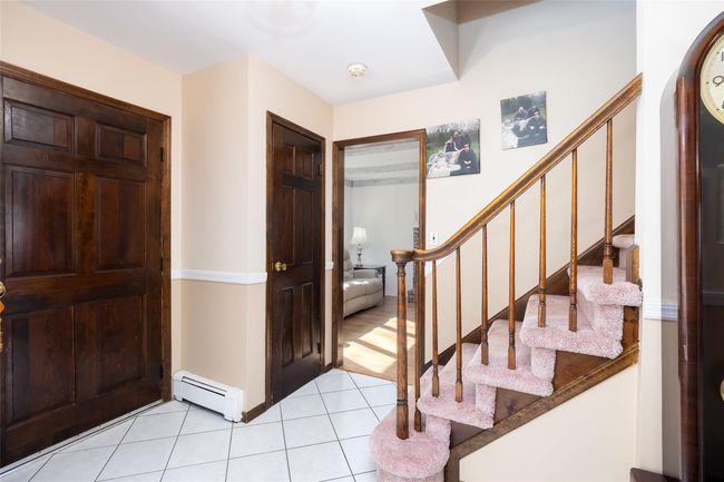 Entrance foyer with light tile patterned floors, baseboard heating, and stairway | Image 5