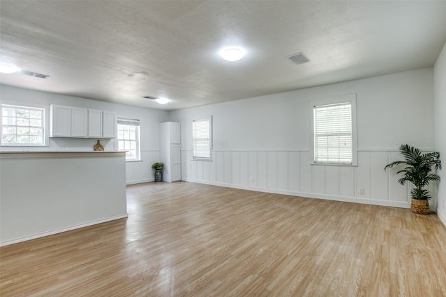 Unfurnished living room featuring light wood-type flooring, wainscoting, and a textured ceiling | Image 4
