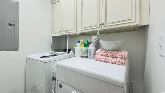 Laundry room featuring independent washer and dryer, electric panel, and cabinet space | Image 16